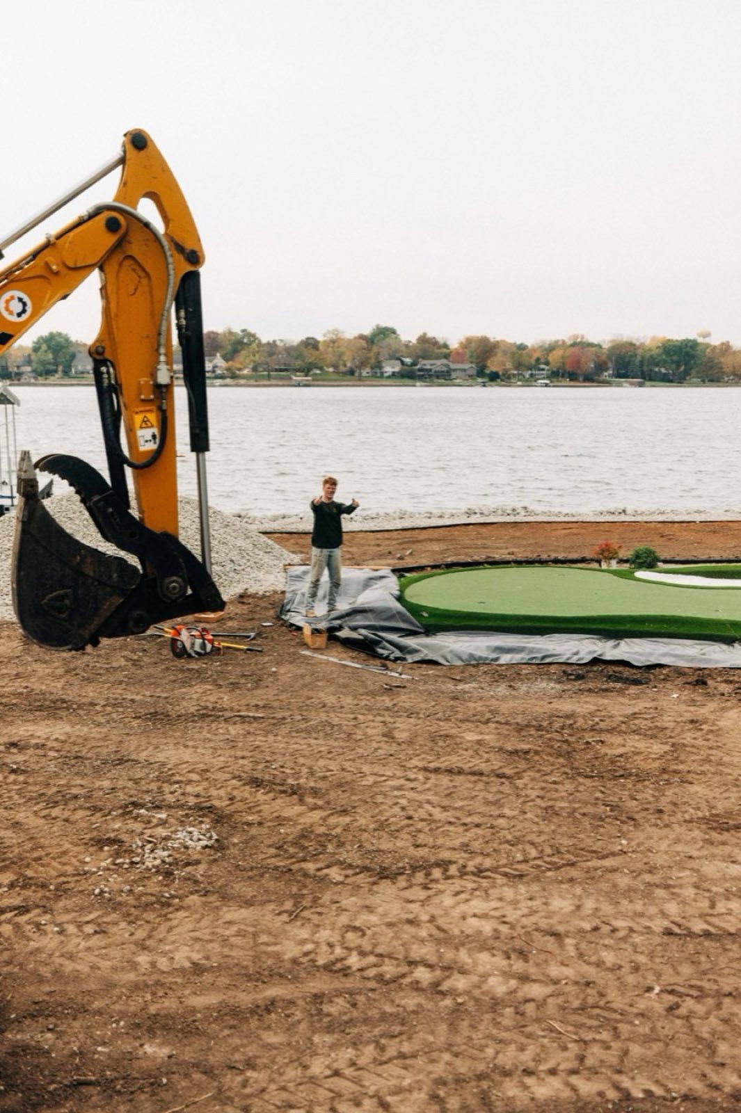 ForeverLawn Kansas City installer on-site at a lakeside putting green project — the local team that does the actual install work