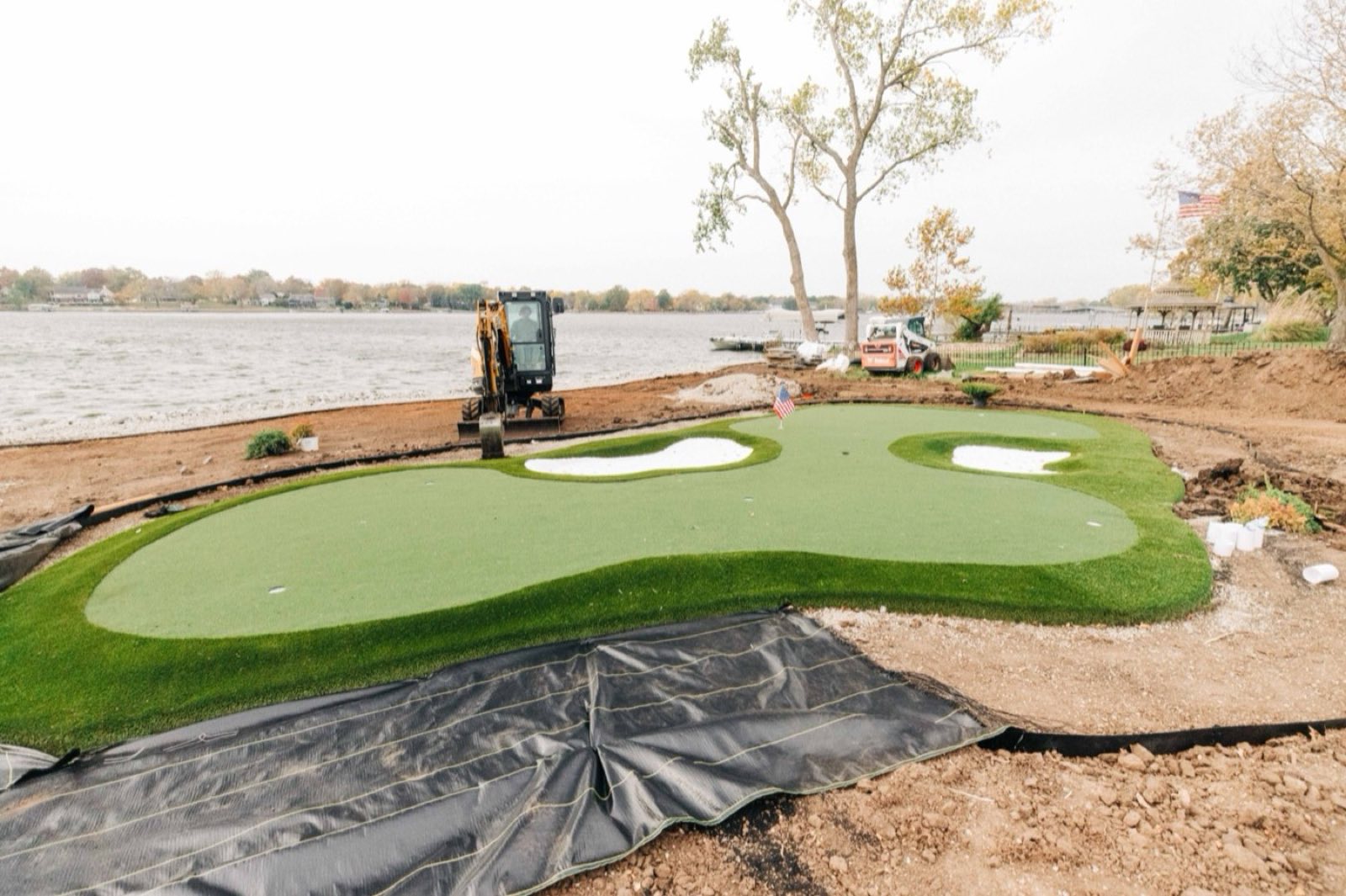 ForeverLawn Kansas City installed lakeside synthetic putting green with multi-tier greens, white waste bunkers, and lake view