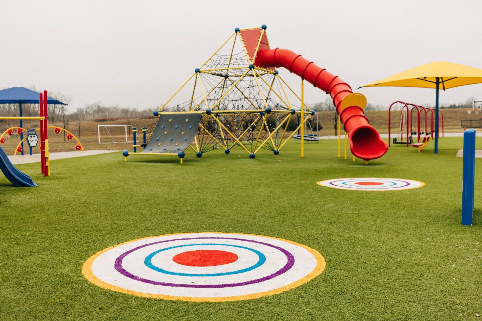 PlaygroundGrass — colorful FLKC play surface install with climbing tower and target circles